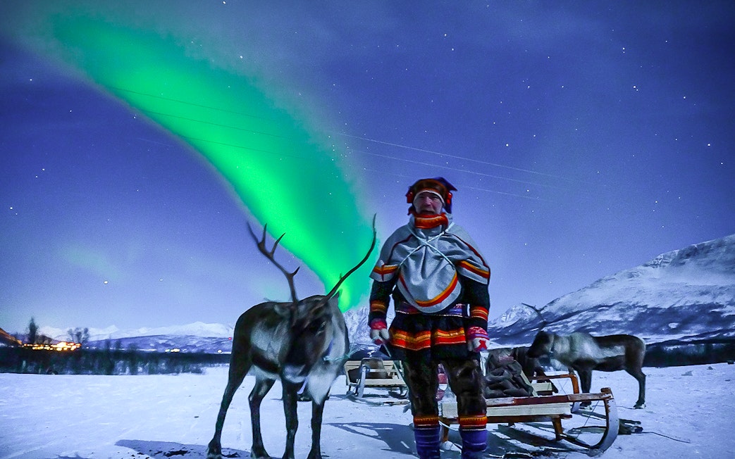 Reindeer sledding under Northern Lights in Tromso, Norway.