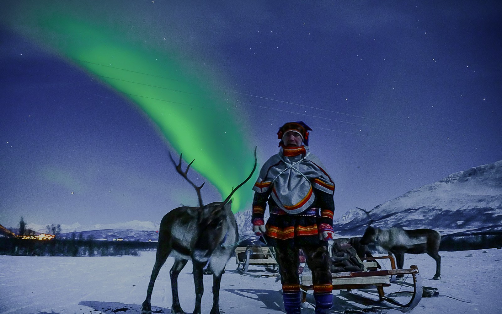 Reindeer sledding under Northern Lights in Tromso, Norway.