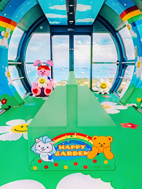 Singapore Flyer capsule interior with colorful cartoon decor and city view.