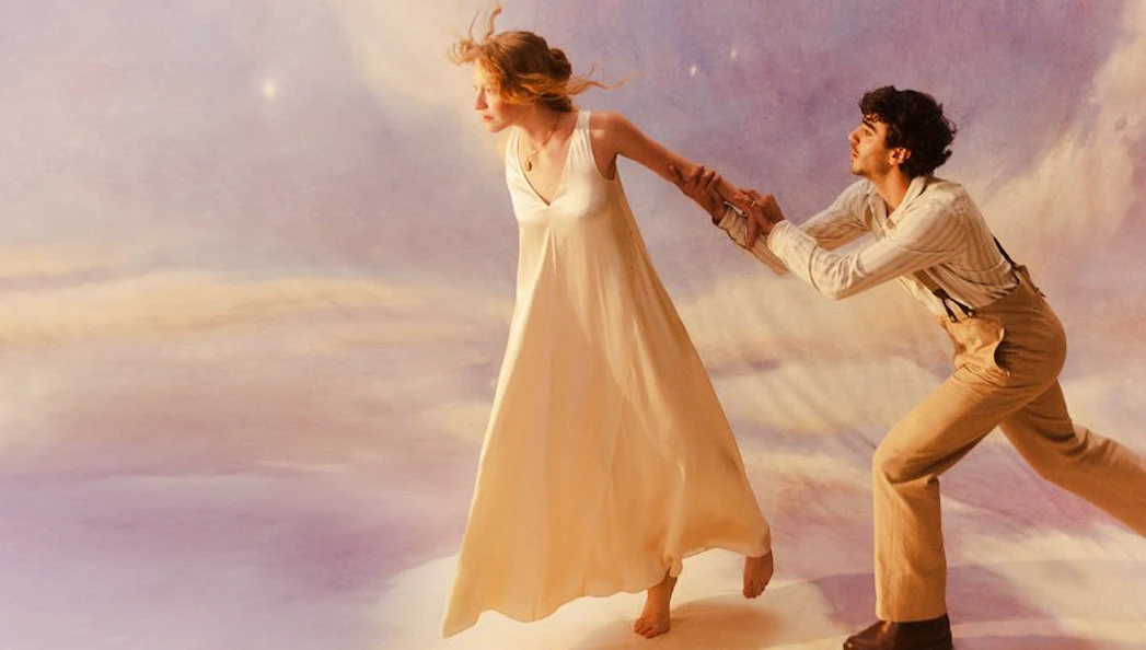 Two performers in a dramatic scene from La Bohème, with a dreamy backdrop.