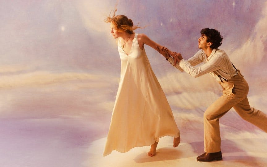 Two performers in a dramatic scene from La Bohème, with a dreamy backdrop.