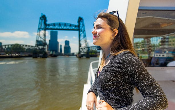 Guest enjoying a river cruise in Rotterdam with the iconic bridge in the background.