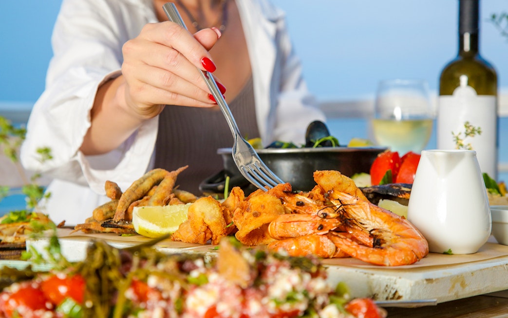 Seafood platter with shrimp and lemon at a beachside table.