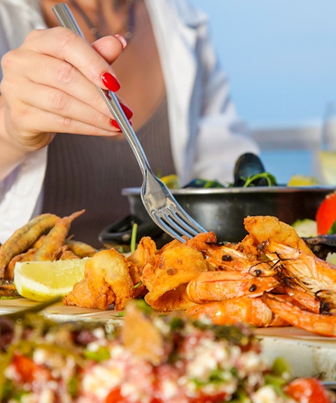 Seafood platter with shrimp and lemon at a beachside table.