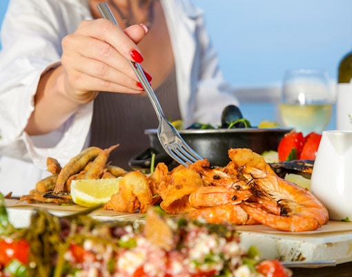 Seafood platter with shrimp and lemon at a beachside table.