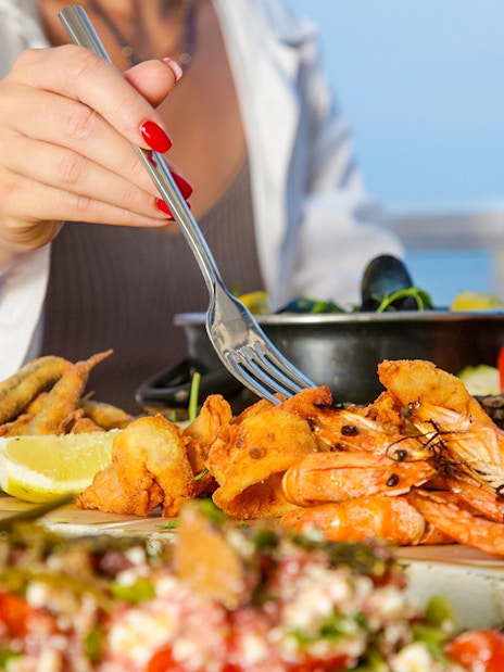 Seafood platter with shrimp and lemon at a beachside table.