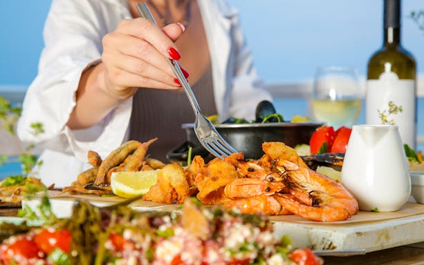 Seafood platter with shrimp and lemon at a beachside table.