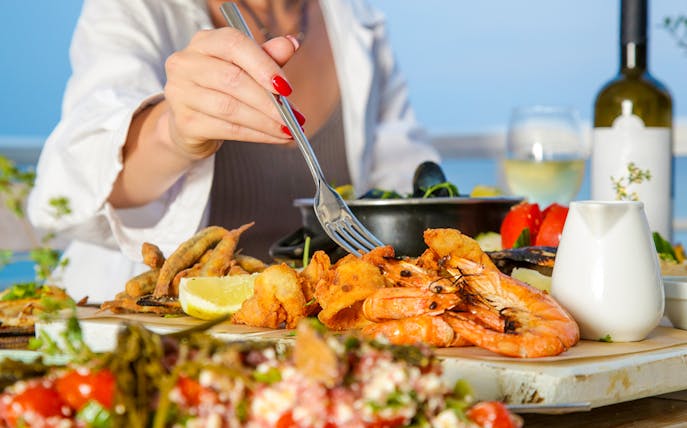Seafood platter with shrimp and lemon at a beachside table.