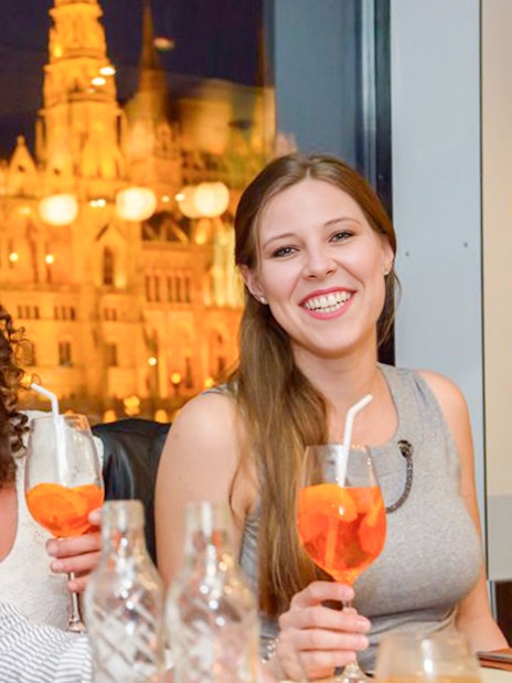 Guests enjoying drinks on Budapest New Year’s Eve cruise with lit Parliament building in background.