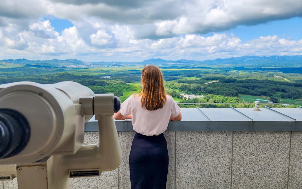 Person viewing landscape at DMZ observatory with telescope.