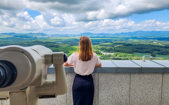 Person viewing landscape at DMZ observatory with telescope.