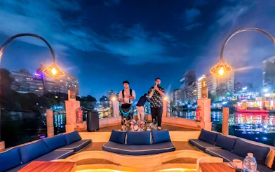 Live band performing on a Nile Dahabiya cruise in Cairo with city lights reflecting on the water.