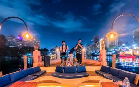 Live band performing on a Nile Dahabiya cruise in Cairo with city lights reflecting on the water.