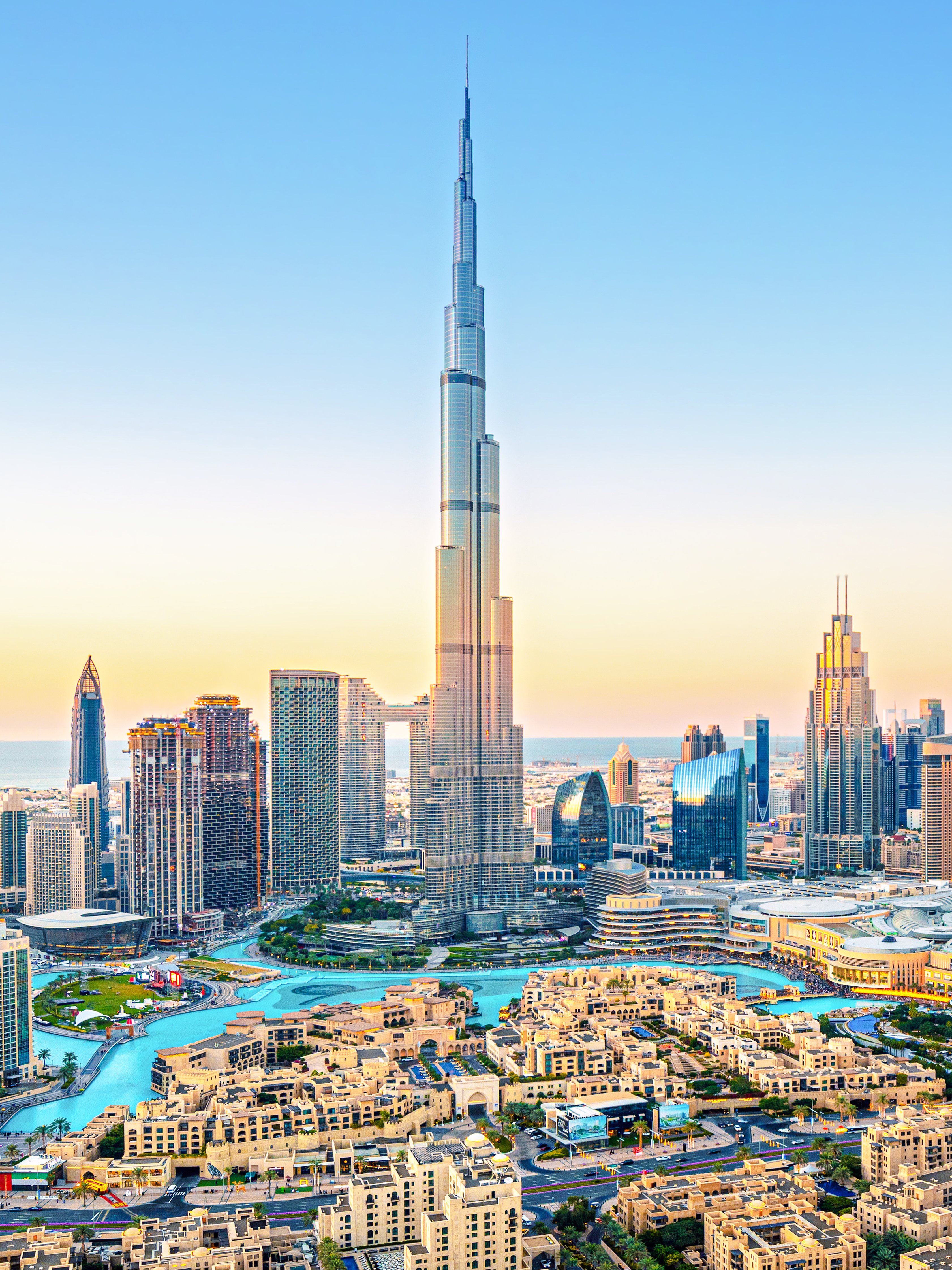 Burj Khalifa towering over downtown Dubai skyline at sunset.
