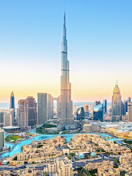 Burj Khalifa towering over downtown Dubai skyline at sunset.