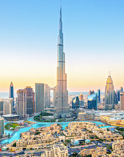 Burj Khalifa towering over downtown Dubai skyline at sunset.