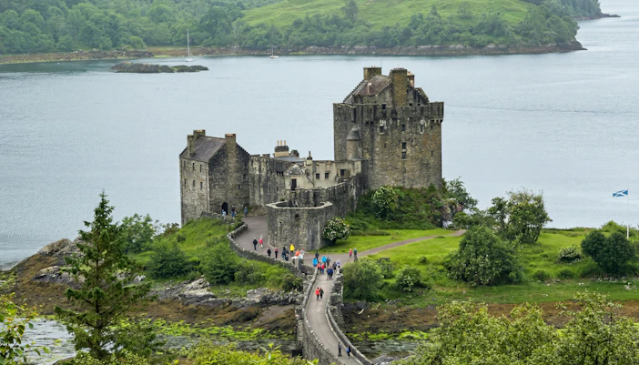 Eilean Donan Castle on a small island with a stone bridge and lush greenery, Scotland.