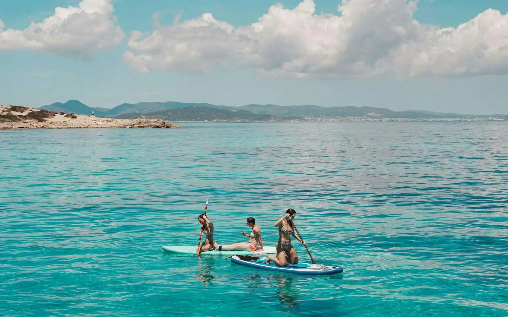 Tourists paddleboarding on clear waters during Ibiza to Formentera cruise.