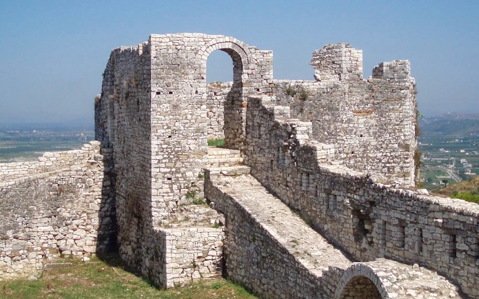 Berat Castle stone walls and archway with distant landscape view.