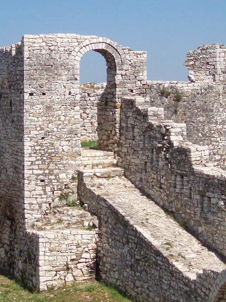 Berat Castle stone walls and archway with distant landscape view.