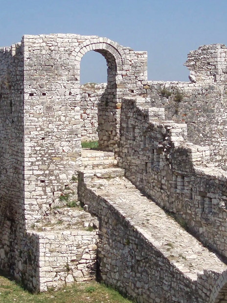 Berat Castle stone walls and archway with distant landscape view.