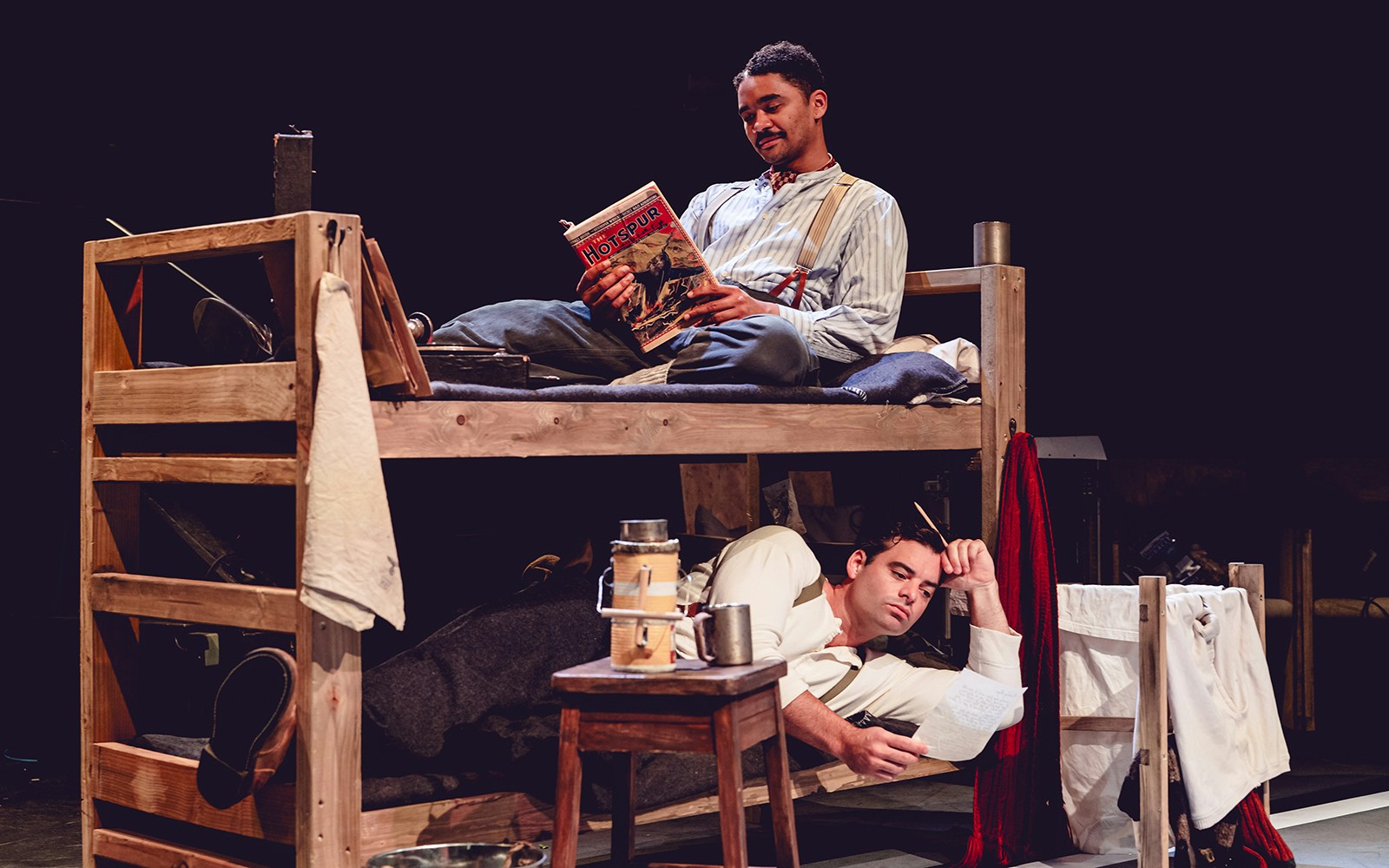 Two men in a bunk bed, one reading a magazine and the other writing, related to Tom, Dick and Harry.