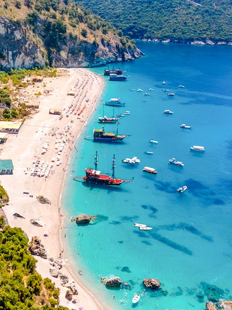 Aerial view of Kroreza Beach, Albania with boats along the shoreline and lush green hills.