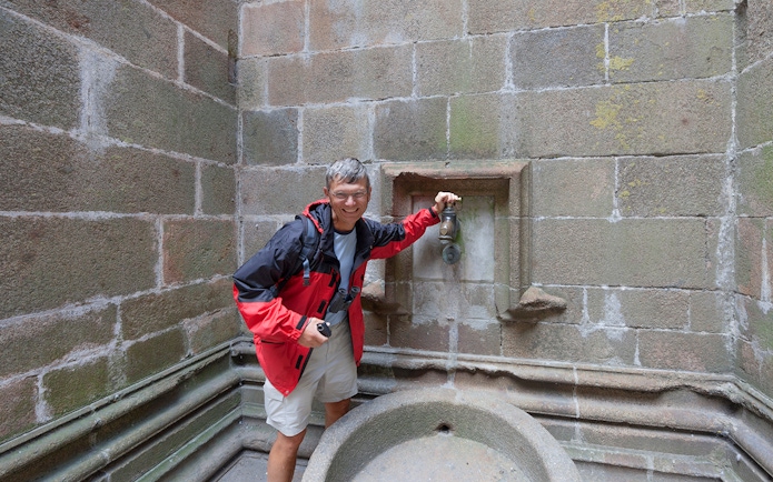 Visitor at Mont Saint-Michel fountain during Paris day trip.
