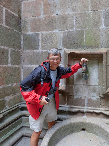 Visitor at Mont Saint-Michel fountain during Paris day trip.