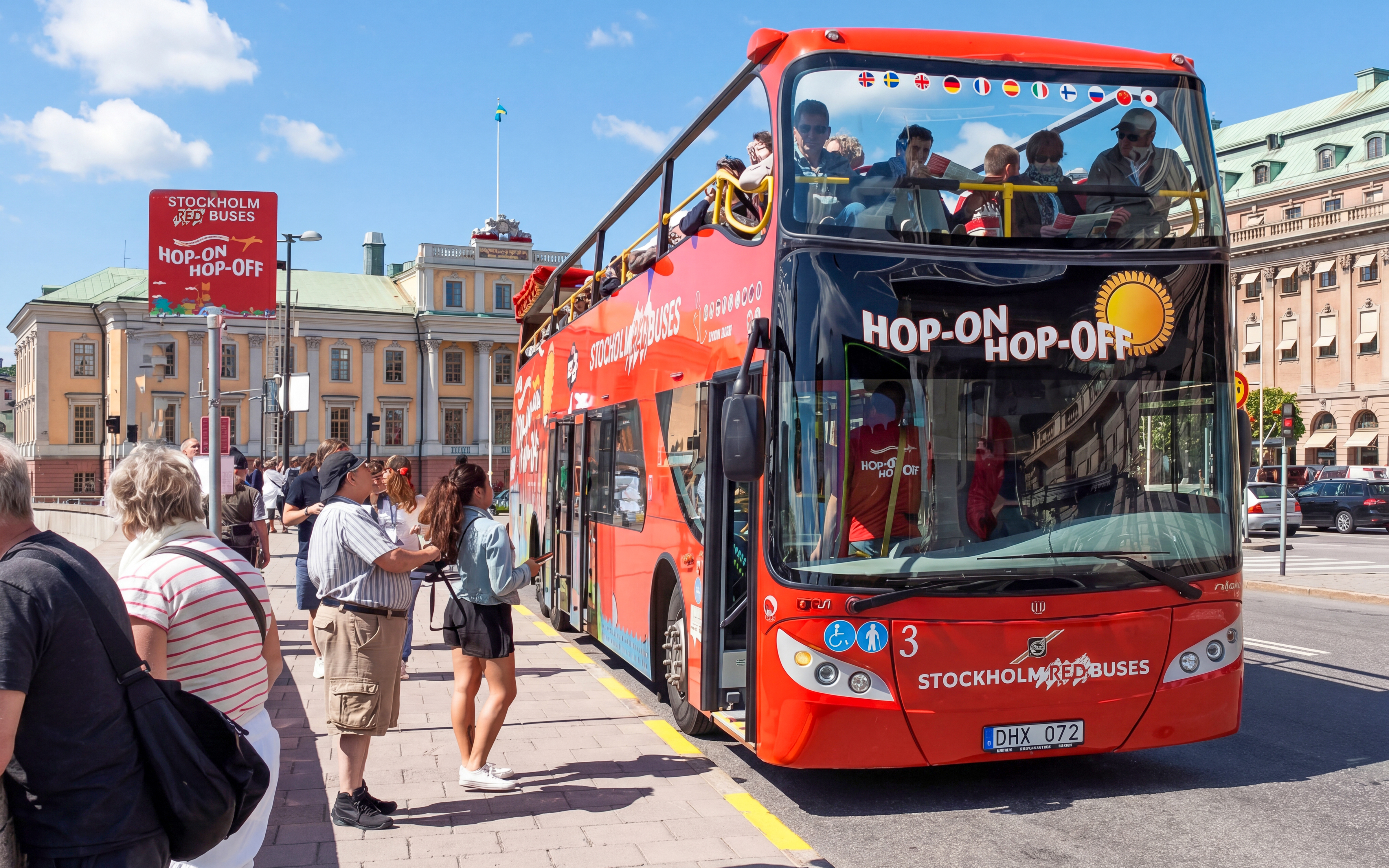 Stockholm hop-on hop-off bus at a stop with tourists boarding.