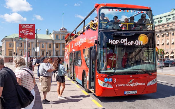 Stockholm hop-on hop-off bus at a stop with tourists boarding.