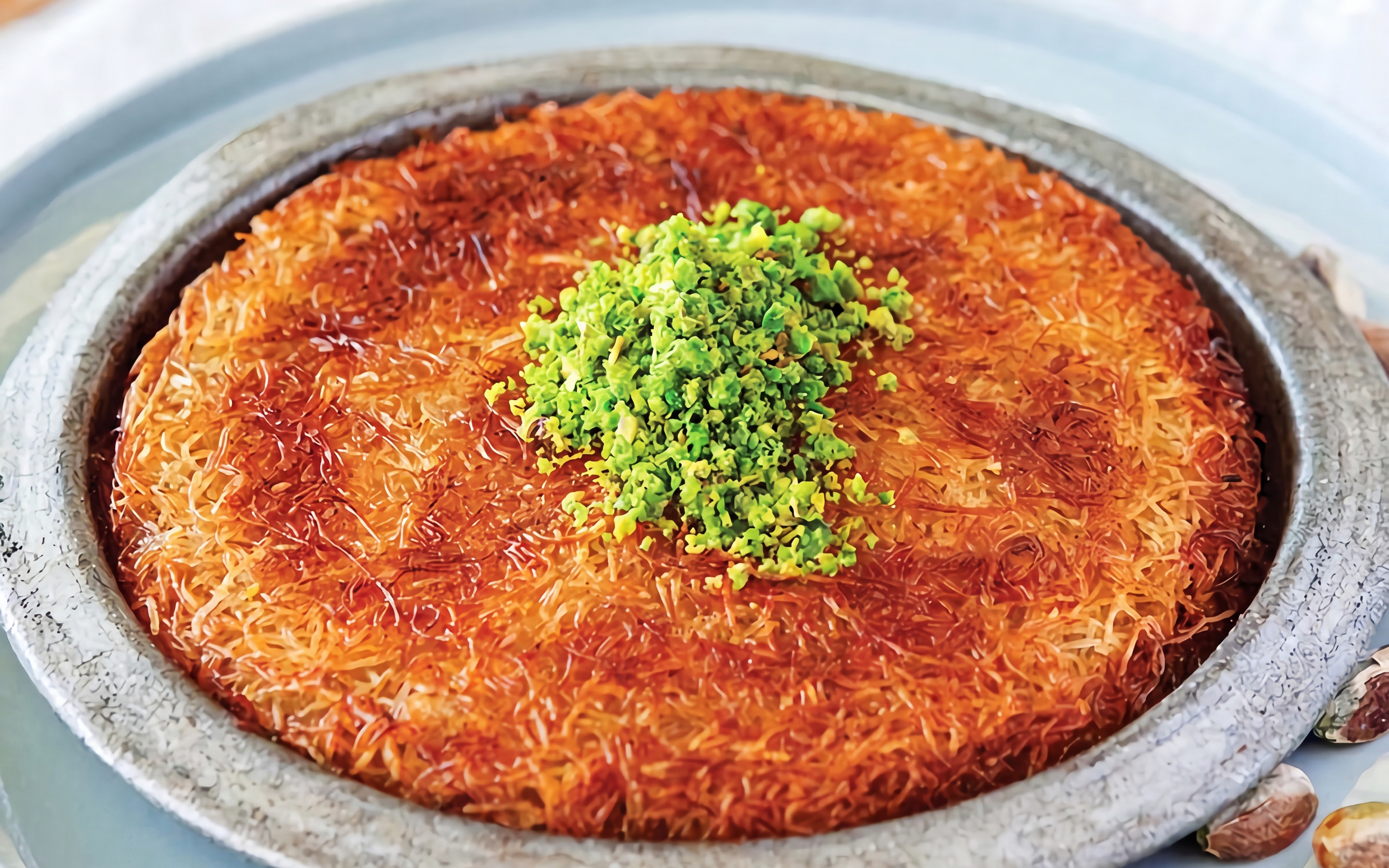 Turkish dessert künefe topped with pistachios, served on a rooftop in Istanbul.
