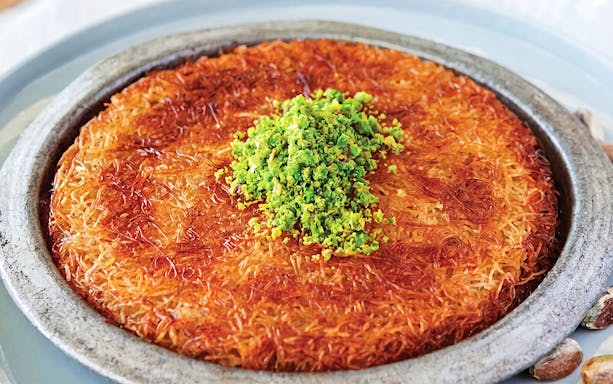 Turkish dessert künefe topped with pistachios, served on a rooftop in Istanbul.