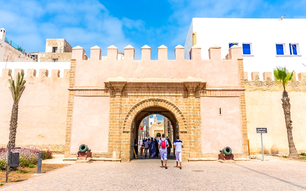 Entrance of the medina in Essaouira, Morocco, with people walking through the historic stone archway.