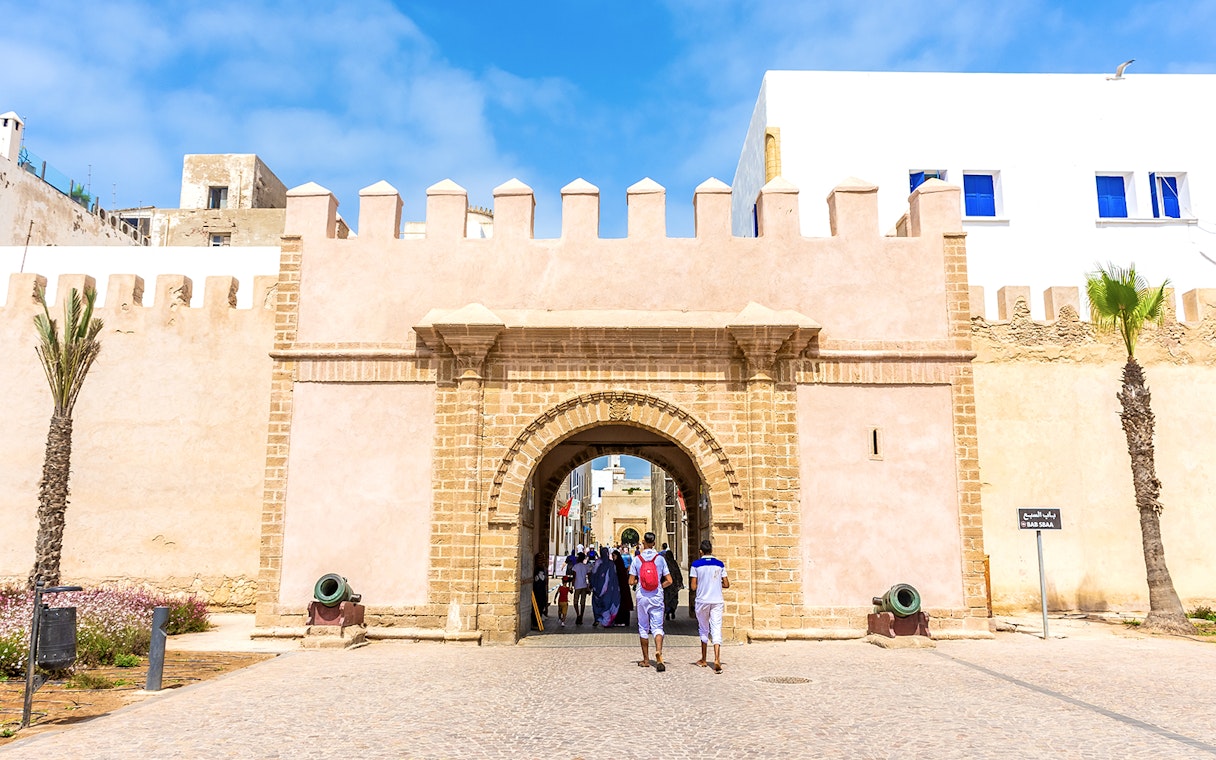 Entrance of the medina in Essaouira, Morocco, with people walking through the historic stone archway.