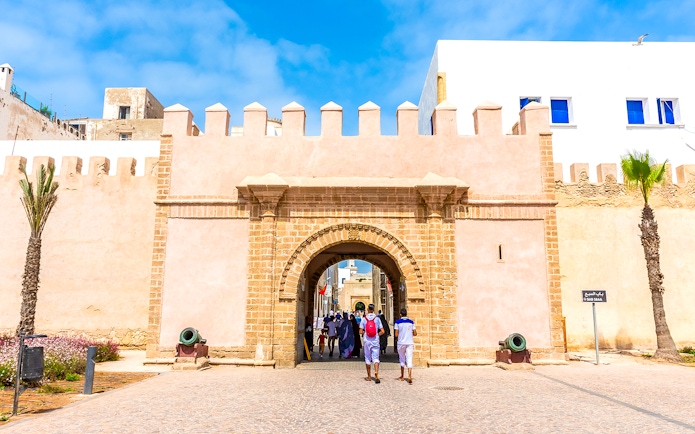 Entrance of the medina in Essaouira, Morocco, with people walking through the historic stone archway.