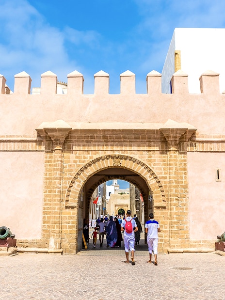 Entrance of the medina in Essaouira, Morocco, with people walking through the historic stone archway.