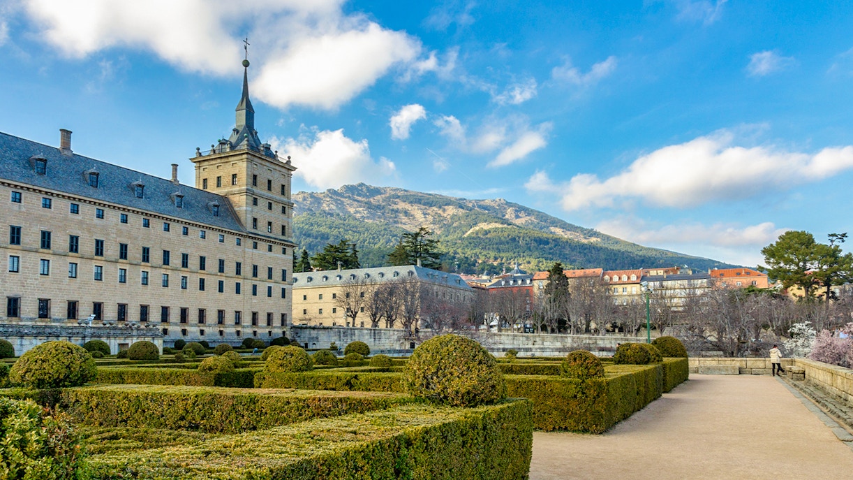 Royal Site of San Lorenzo de El Escorial with gardens and mountain backdrop.