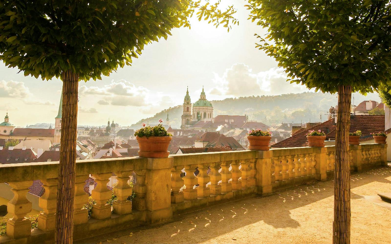 Prague Castle view from a terrace with trees and potted plants.