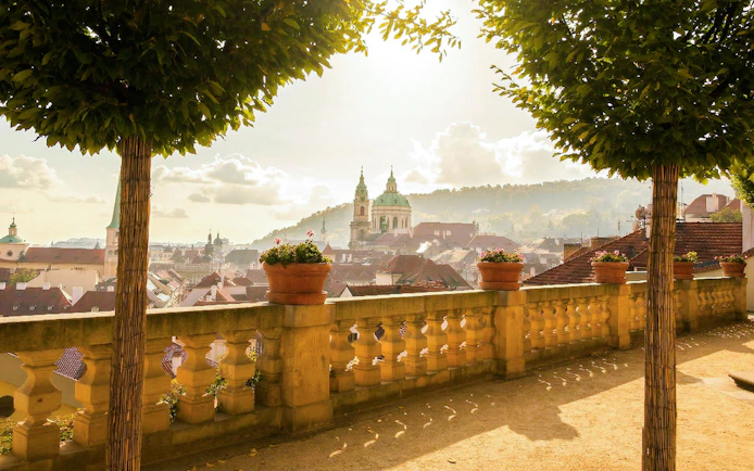 Prague Castle view from a terrace with trees and potted plants.