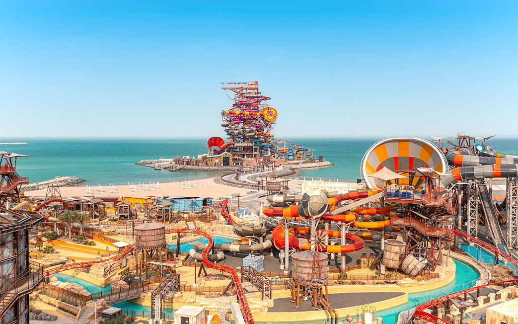 Aerial view of colorful water slides at Meryal Waterpark by the sea.