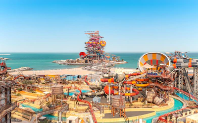Aerial view of colorful water slides at Meryal Waterpark by the sea.