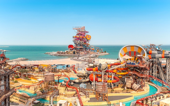 Aerial view of colorful water slides at Meryal Waterpark by the sea.