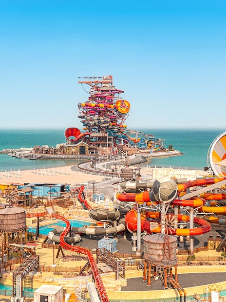 Aerial view of colorful water slides at Meryal Waterpark by the sea.