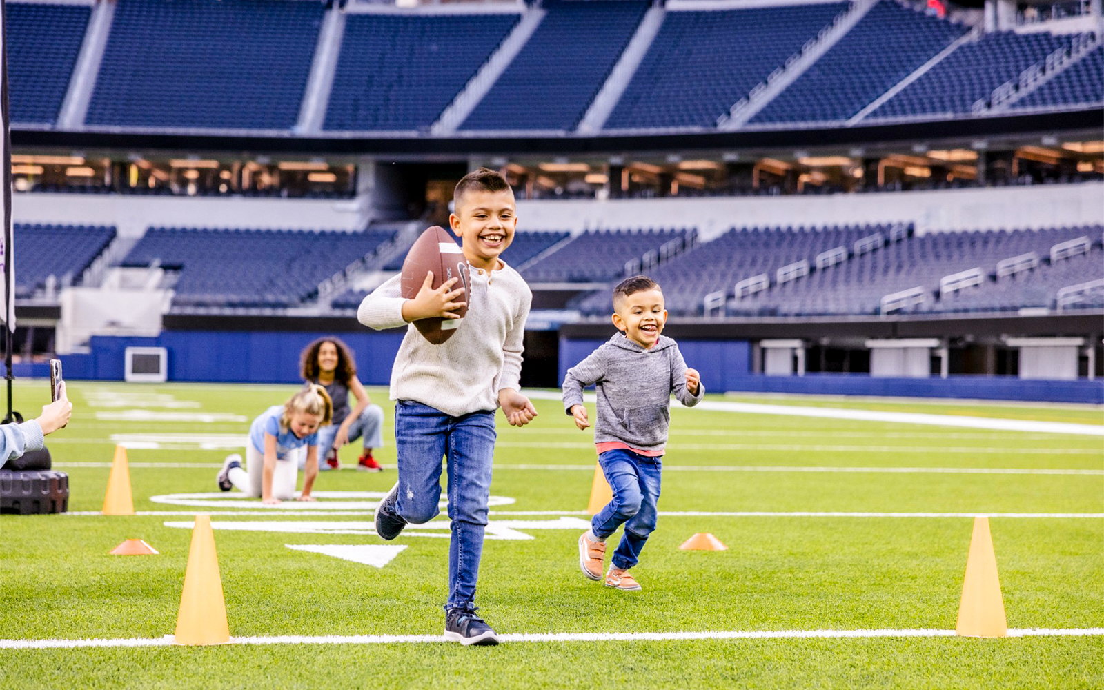 Children playing football on a field in Los Angeles stadium, part of Go City Pass experience.