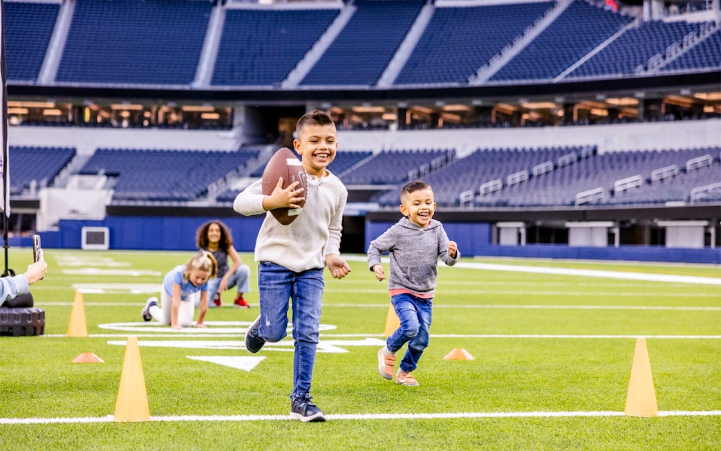 Children playing football on a field in Los Angeles stadium, part of Go City Pass experience.