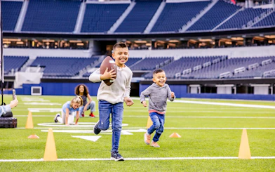 Children playing football on a field in Los Angeles stadium, part of Go City Pass experience.