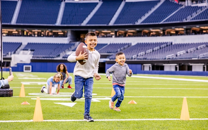 Children playing football on a field in Los Angeles stadium, part of Go City Pass experience.