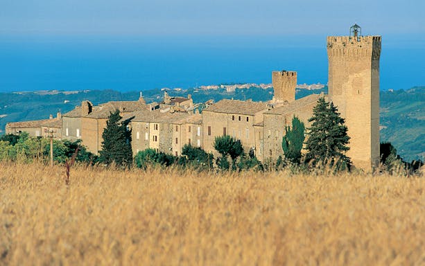 Medieval village with stone towers and buildings near the sea, Italy, Free Vespa Tour.