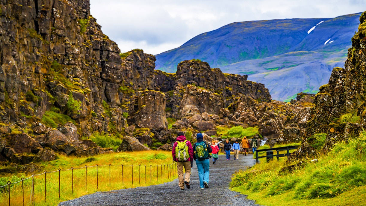 Tour group walking through Thingvellir National Park's rocky landscape on Reykjavik's Golden Circle tour.